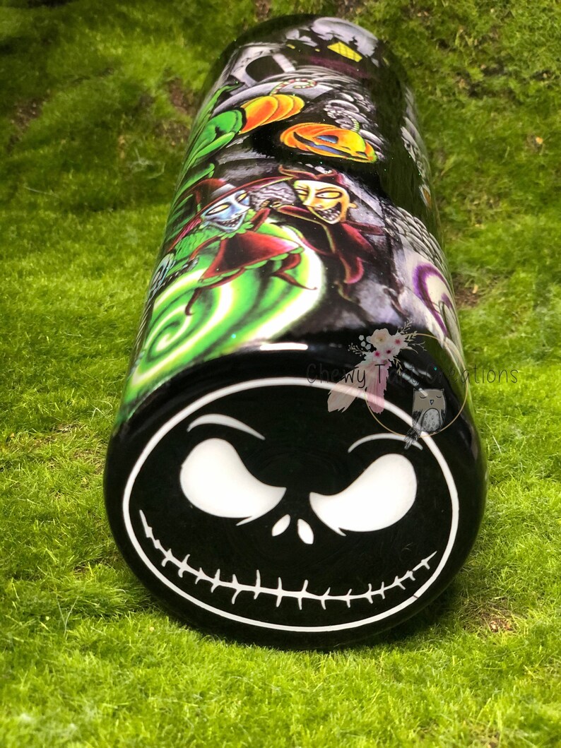 Puede incluir: Un vaso negro y verde con un dise&ntilde;o de Pesadilla Antes de Navidad. El vaso presenta una imagen en blanco y negro de la cara de Jack Skellington en la parte inferior.