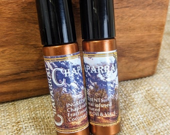 Pode incluir: Duas garrafas de vidro âmbar com tampas pretas. As garrafas são etiquetadas com "Chaparral" e listam os ingredientes: Chaparral, óleo de coco fracionado e vitamina E.