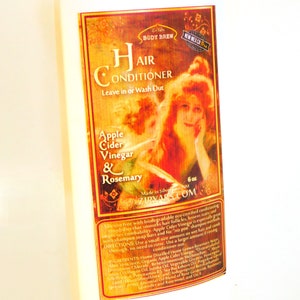 May include: A 6-ounce bottle of hair conditioner with a vintage-style label featuring a woman with red hair. The label is gold and features the text "Hair Conditioner", "Apple Cider Vinegar & Rosemary", and "Ziryabs.com".