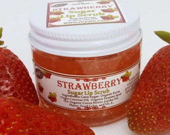 May include: A small glass jar with a white lid filled with a red strawberry sugar lip scrub. The jar has a label that says "Strawberry Sugar Lip Scrub" and lists the ingredients. The jar is surrounded by fresh strawberries.