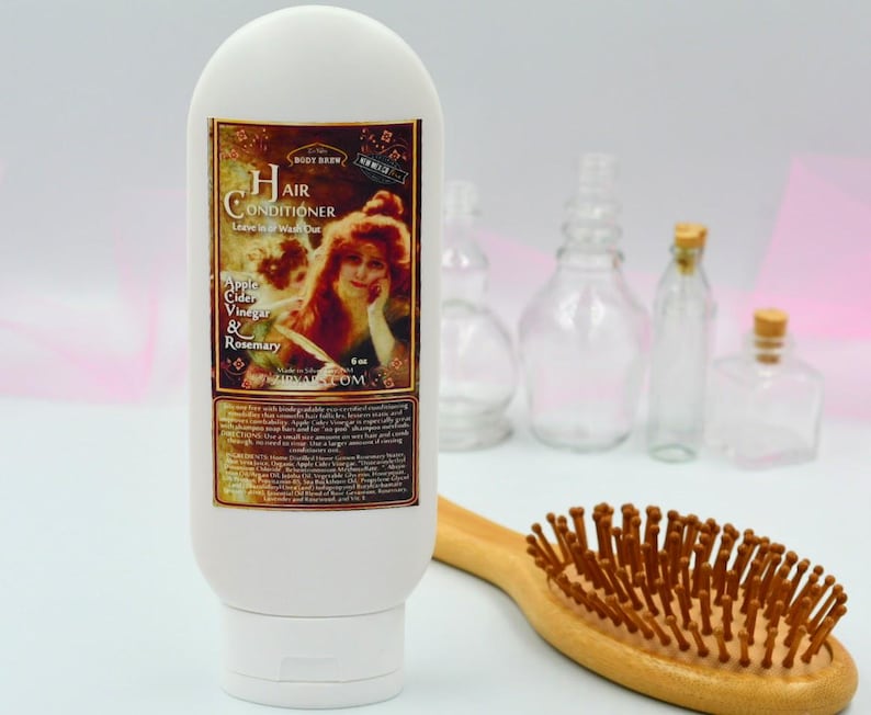 May include: White bottle of hair conditioner with a vintage label featuring a woman with red hair. The label reads "Hair Conditioner Leave-in or Wash Out Apple Cider Vinegar & Rosemary".