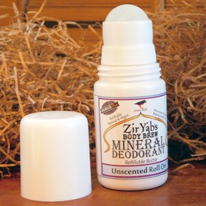May include: White roll-on deodorant bottle with a black and white label that reads "Zir Yabs Body Brew Mineral Deodorant Refillable Bottle Unscented Roll On".