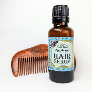 Pu&ograve; includere: Una bottiglia di vetro marrone con un tappo nero e un'etichetta blu e bianca che recita "Zir Yaby Body Brew Andalusian Precious Oils Hair Serum 1 FL OZ".