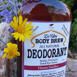 以下が含まれることがあります： 黒いキャップと「Zir Yabs Body Brew All Natural Deodorant Flower Garden Works 24 Hours! Good-bye Stains 6 oz」と書かれたラベルが付いた茶色のガラス瓶。瓶は花に囲まれている。