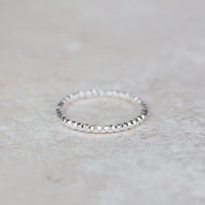 May include: A silver ring with a textured, diamond-shaped pattern.