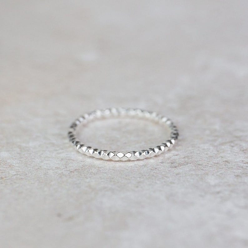 Puede incluir: Un anillo de plata con un patr&oacute;n texturizado en forma de diamante.