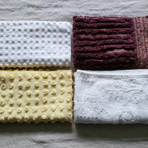 May include: Four white cotton bath mats with different textures. One mat has a raised dot pattern, one has a raised circle pattern, one has a raised diamond pattern, and one has a raised stripe pattern.