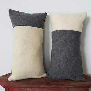 May include: Two decorative pillows with a two-tone design. One pillow is gray with a white top, and the other is white with a gray top.