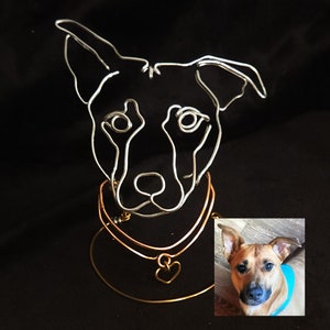 May include: Wire sculpture of a dog's head with a gold heart charm on a copper and gold collar. A photo of a similar dog is shown in the lower right corner.