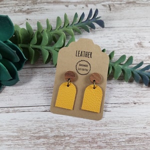 May include: A pair of yellow leather earrings with a wood accent. The earrings are on a card that says "Leather Handmade Just for You".