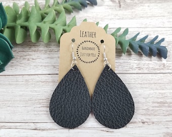 May include: Black leather teardrop earrings with silver hooks. The earrings are on a brown card with the text "Leather Handmade Just For You".