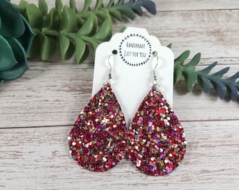 May include: Red, gold, silver, and pink glitter teardrop earrings with silver hooks. The earrings are on a white card with the text "Handmade Just For You".
