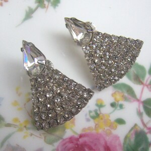 May include: A pair of silver tone earrings with a teardrop shaped crystal and a fringe of rhinestones.