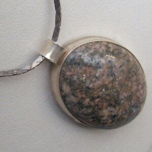 May include: A silver chain necklace with a pendant featuring a round, grey and pink stone set in a silver bezel.