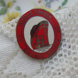 May include: A red and white enamel pin featuring a ship silhouette and the text "Holland America Line 50 Mariner Society".