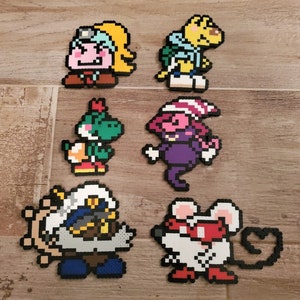 Könnte beinhalten: Set mit 7 Pixel-Art-Charakteren aus bunten Perlen. Die Charaktere umfassen einen pinkfarbenen und gelben Charakter mit einem blauen Hut, einen gelben Charakter mit einem blauen Hemd, einen grünen Charakter mit einem roten Hut, einen lilafarbenen Charakter mit einem pinkfarbenen und weißen Hut, einen weißen Charakter mit einem blauen Hut und einen weißen Charakter mit einer roten Nase.