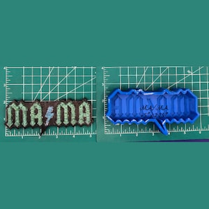 May include: A blue silicone mould for making a "MAMA" cake topper. The mould is 5 inches long and 2.25 inches wide. The mould is on a green cutting mat.