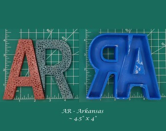 Op de afbeelding: Twee sets letters, "AR", gemaakt van verschillende materialen. De eerste set is rood en heeft een textuur, de tweede set is blauw en glad. Beide sets zijn ongeveer 4,5 inch bij 4 inch.
