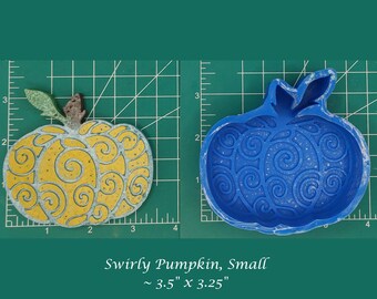 Puede incluir: Un molde de silicona azul con forma de calabaza con un patrón de espiral. El molde mide aproximadamente 3,5 pulgadas por 3,25 pulgadas.