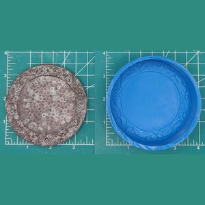 Op de afbeelding: Een tweedelige siliconen mal voor het maken van een ronde harsbak met een decoratieve rand. De mal is blauw en de bak is bruin met een getextureerd oppervlak.