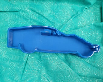 May include: A blue plastic cookie cutter shaped like a race car. The cutter is designed to create cookies in the shape of a race car.