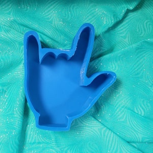 May include: A blue silicone mould shaped like a hand making the 'I love you' sign language gesture.