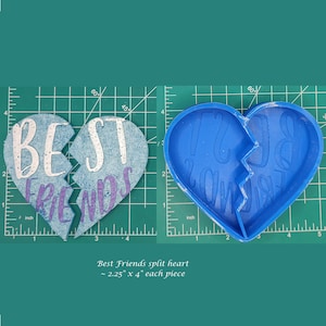 May include: Two blue silicone molds shaped like a heart, each half reads "Best Friends" in white lettering. The molds are on a green cutting mat with inch markings.
