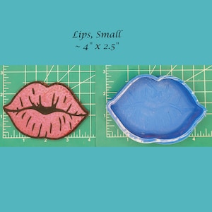 May include: A pink silicone mold of lips, with a black outline, on a green cutting mat. The mold is approximately 4 inches by 2.5 inches.