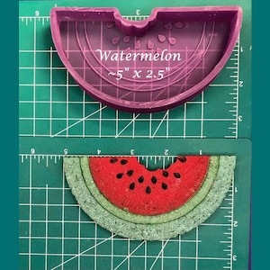 May include: A purple silicone mold shaped like a watermelon slice. The mold is 5 inches by 2.5 inches. A finished watermelon slice made from the mold is shown on a green cutting mat.