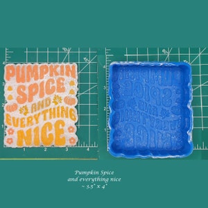 May include: Blue silicone mold for resin crafts. The mold is shaped like a square with rounded corners and features the text "Pumpkin Spice and Everything Nice". The mold measures approximately 3.5 inches by 4 inches.