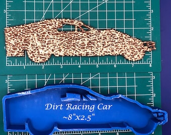 May include: A blue silicone mold shaped like a dirt racing car. The mold is on a green cutting mat with white markings. The mold is approximately 8 inches long and 2.5 inches wide. The text "Dirt Racing Car ~8"x2.5"" is printed on the mold.
