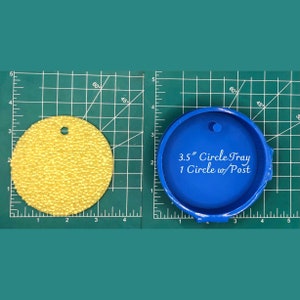 Op de afbeelding: Een blauwe siliconen mal voor het maken van een ronde dienblad van 8,9 cm met een pen. De mal ligt op een groene snijmat met inchmarkeringen.