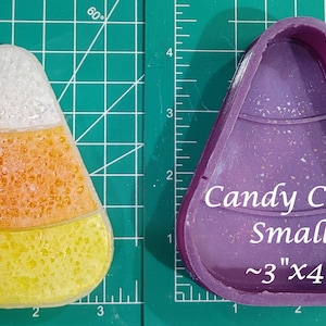 May include: Purple silicone mould for making candy corn shaped treats. The mould is 3 inches by 4 inches and is shown next to a finished candy corn treat.