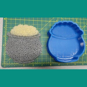 May include: A blue plastic mould of a pot of gold, with a separate mould of gold coins to be placed inside the pot.