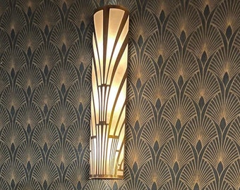 May include: A gold and black geometric patterned wallpaper with a decorative light fixture in the center. The light fixture is a cylindrical shape with a geometric design and a white frosted glass shade.