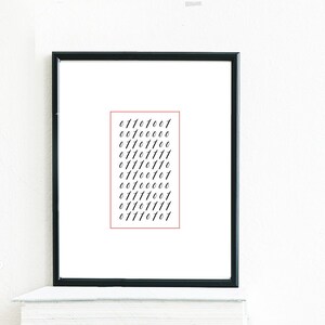 May include: A black rectangular frame containing a white print with ten lines of black binary code digits. The frame rests on a stack of various books next to a clear glass plant mister with a metal nozzle sitting on a square tile with a pattern.