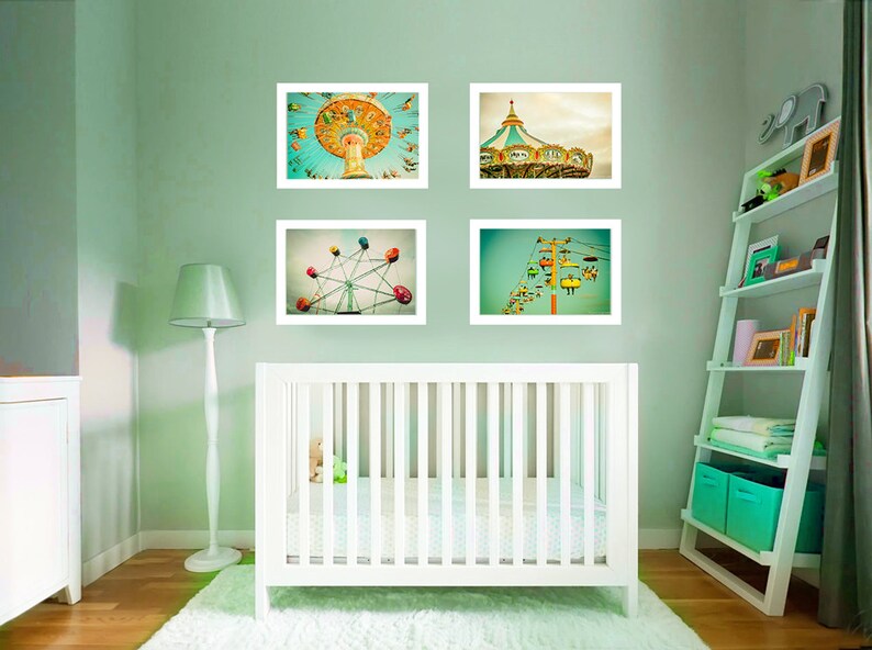 May include: Four framed prints of amusement park rides hang above a white crib in a nursery. The prints depict a carousel, Ferris wheel, swing ride, and ski lift. The room is painted a light green color.