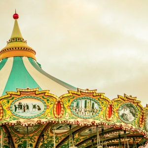 May include: A colorful carousel roof with a striped teal and white canopy. The ornate trim features painted scenes and is accented with gold and red details. A red ball tops the carousel's spire.