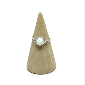 May include: A silver wire wrapped ring with a white opal gemstone.