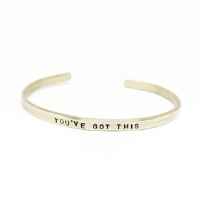 May include: Silver bangle bracelet with the words "You've Got This" engraved on the front.