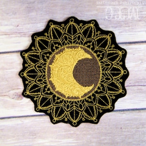 May include: A black and gold embroidered patch featuring a crescent moon design within a circular mandala. The moon is gold with intricate detailing, set against a brown background. The outer edge is a scalloped design.