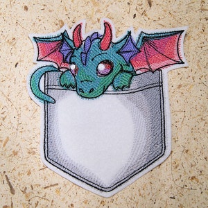 May include: Embroidered patch of a green, purple, and red dragon peeking out of a gray pocket. The dragon has large eyes and a toothy grin.