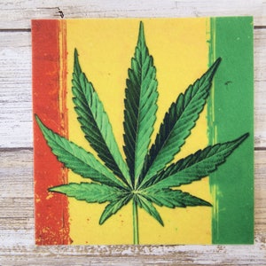 May include: A green marijuana leaf with a yellow background and red and green borders.