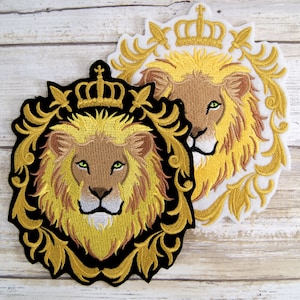 May include: Two embroidered patches featuring a lion's head with a crown above it. The lion's mane is yellow and brown, and the crown is gold. The patches are on a white background.