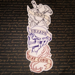 May include: White embroidered patch featuring a skull and crossbones design. The skull is blue and the crossbones are red. The patch includes the words "What Dreams May Come" embroidered in a banner.