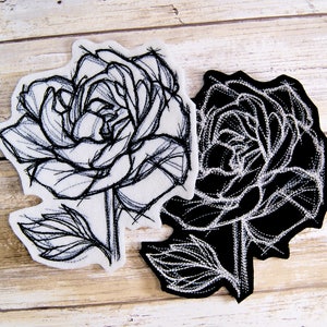 Peut inclure: Deux patchs en tissu brodés représentant des roses en noir et blanc.