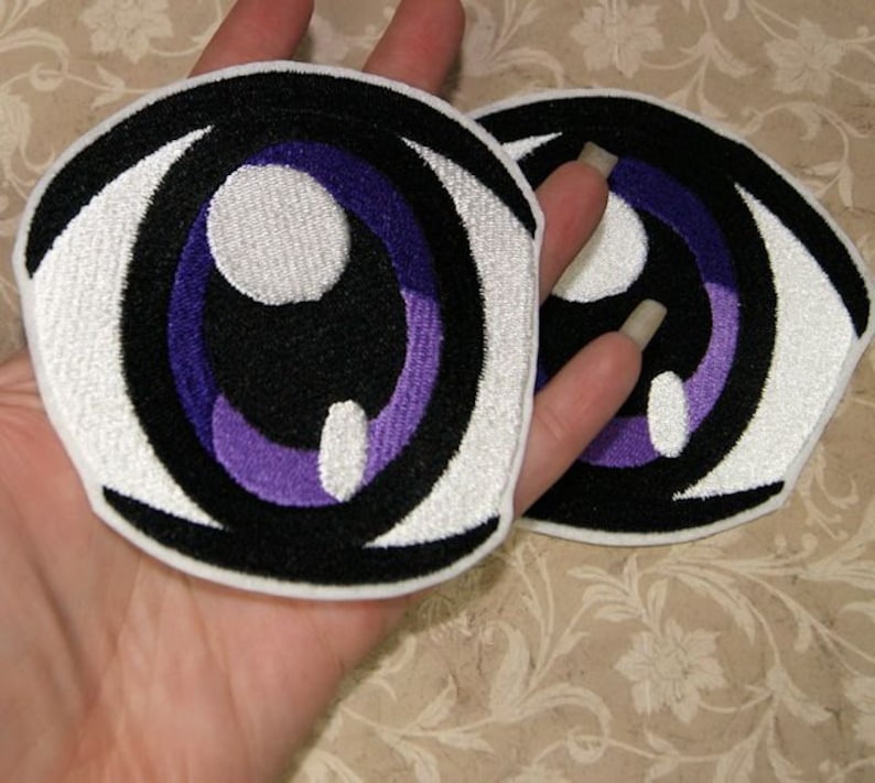 May include: Two white and black embroidered iron-on patches of anime eyes with purple irises.