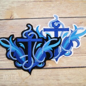 May include: Two blue embroidered iron-on patches featuring anchors with rope details and blue and black floral designs.
