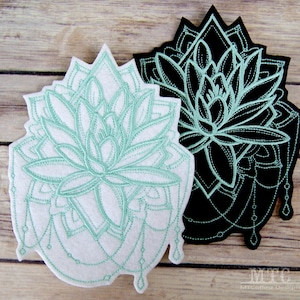 May include: Two embroidered patches featuring a stylised lotus flower design. The patches are made of felt and have a white background with a light green outline. The second patch is black with a light green outline.