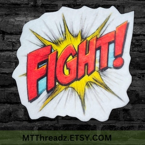 May include: A comic book-style sticker with the word "FIGHT!" in red, outlined in black, set against a yellow burst. The sticker has a white border and a blue accent. The Etsy shop URL is at the bottom.
